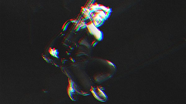 Person mid-air holding an electric guitar, captured in a dynamic pose with bent legs and arms gripping the instrument; glitch effect with red and blue outlines enhances the vibrant look against a dark background.