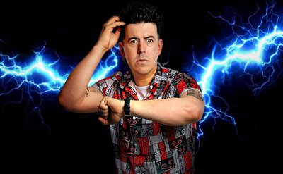 A person wearing a grey and red short sleeved shirt looks at their watch and scratches their head with a concerned look on their face. A bolt of blue lightening goes across the dark background behind them.