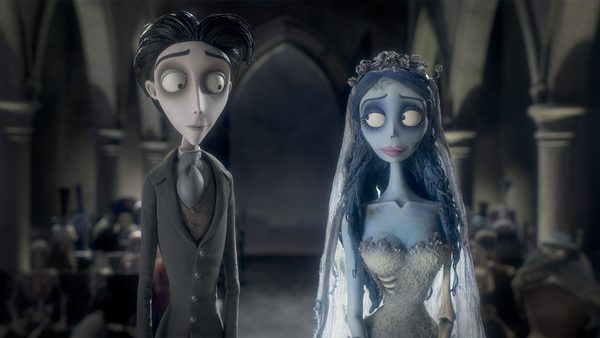 Two animated characters stand in a dimly lit gothic cathedral; one wears a formal suit with neatly styled dark hair, the other a tattered wedding dress with a veil and flower-adorned hair, set against arched windows and columns.
